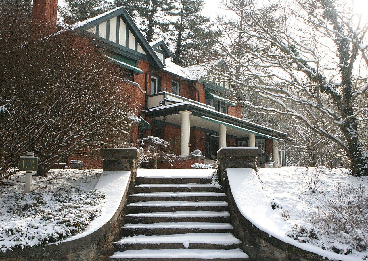 Stone steps leading up to a brick house porch, covered in snow on Macon Avenue in Asheville