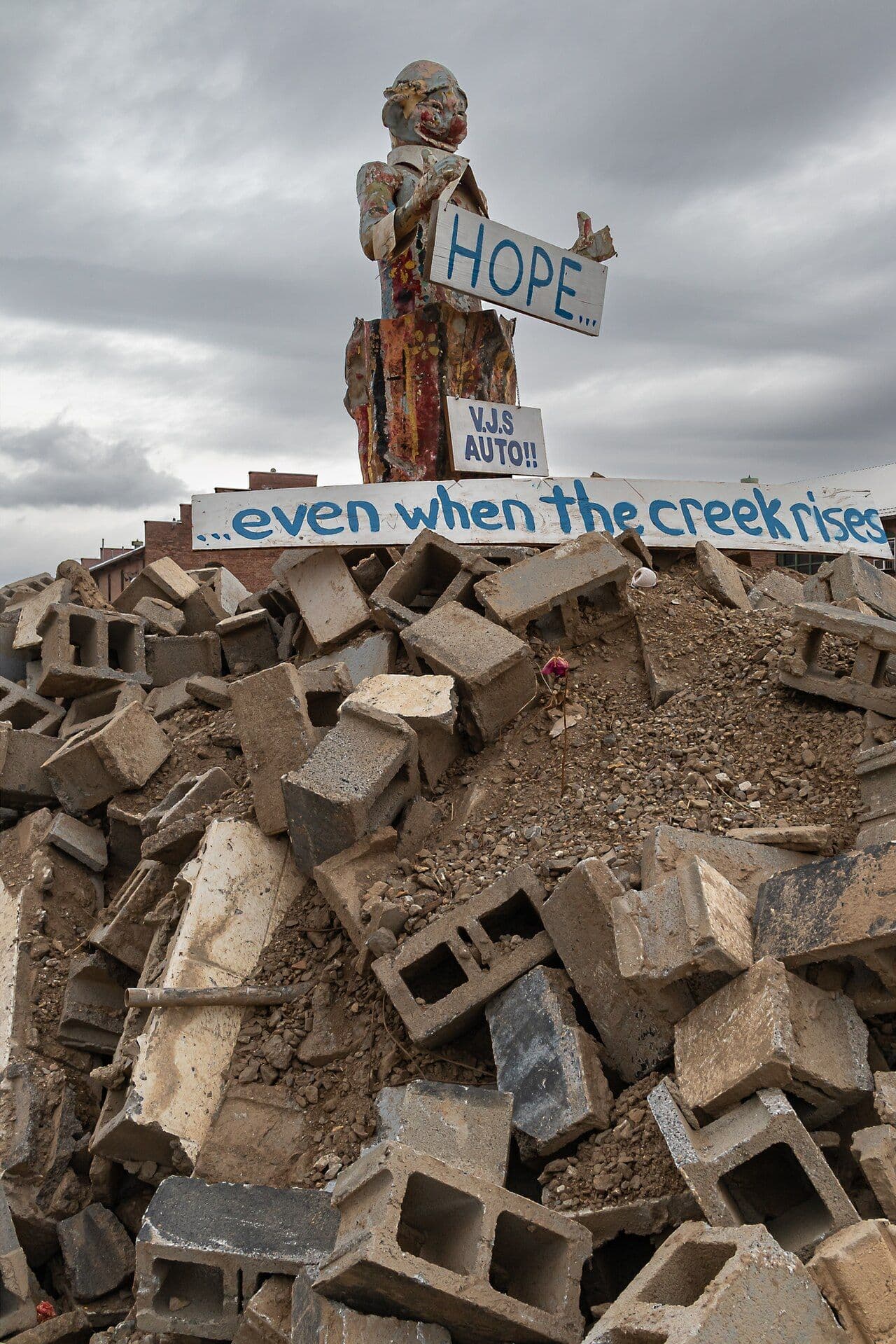 Hand-painted HOPE sign and carved figure on top of a pile of cinder blocks and debris in the River Arts District after Hurricane Helene