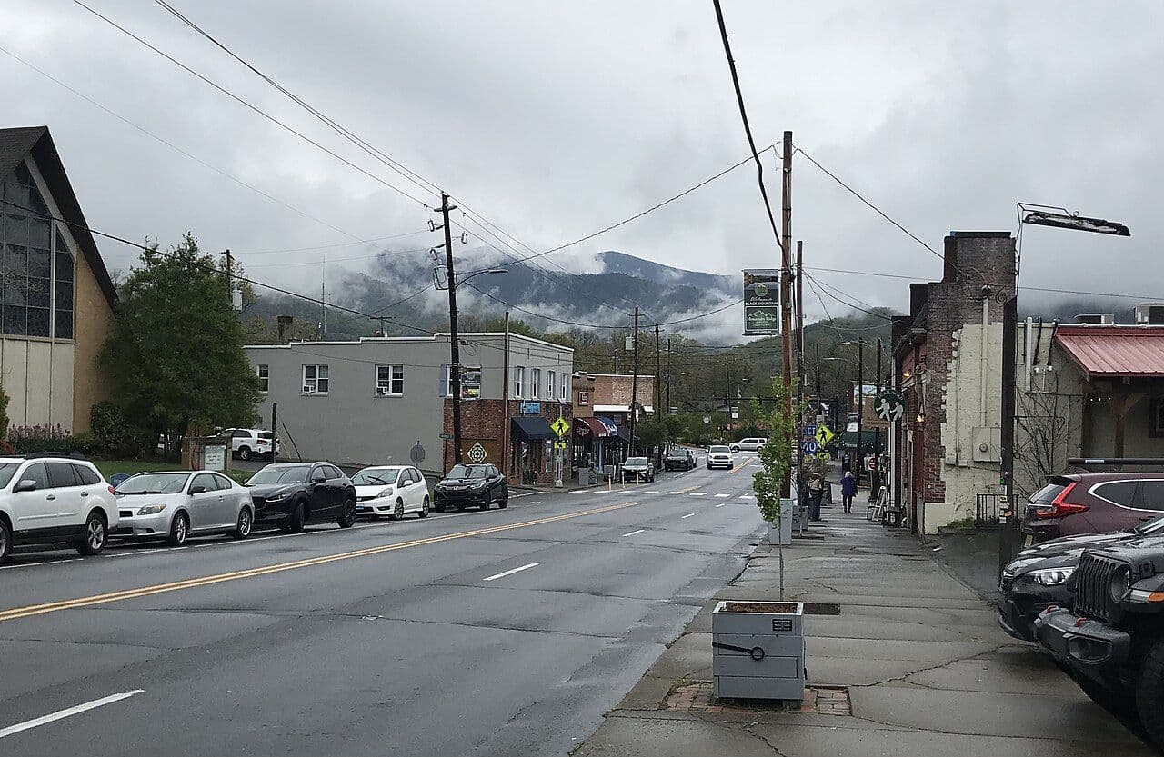 Shops and parked cars along State Street in downtown Black Mountain with mountains behind