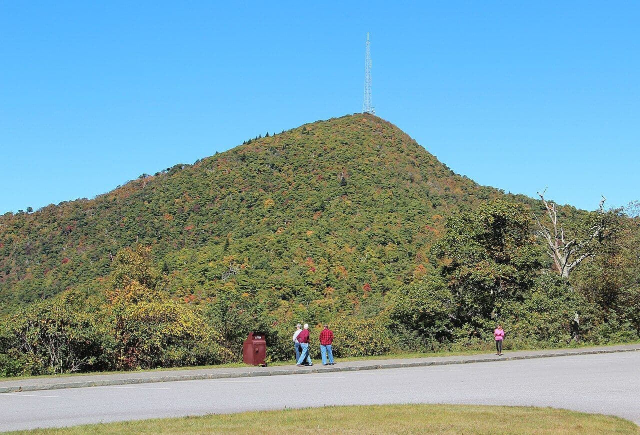 Green, forested Mount Pisgah rising above the Blue Ridge Parkway on a clear autumn day