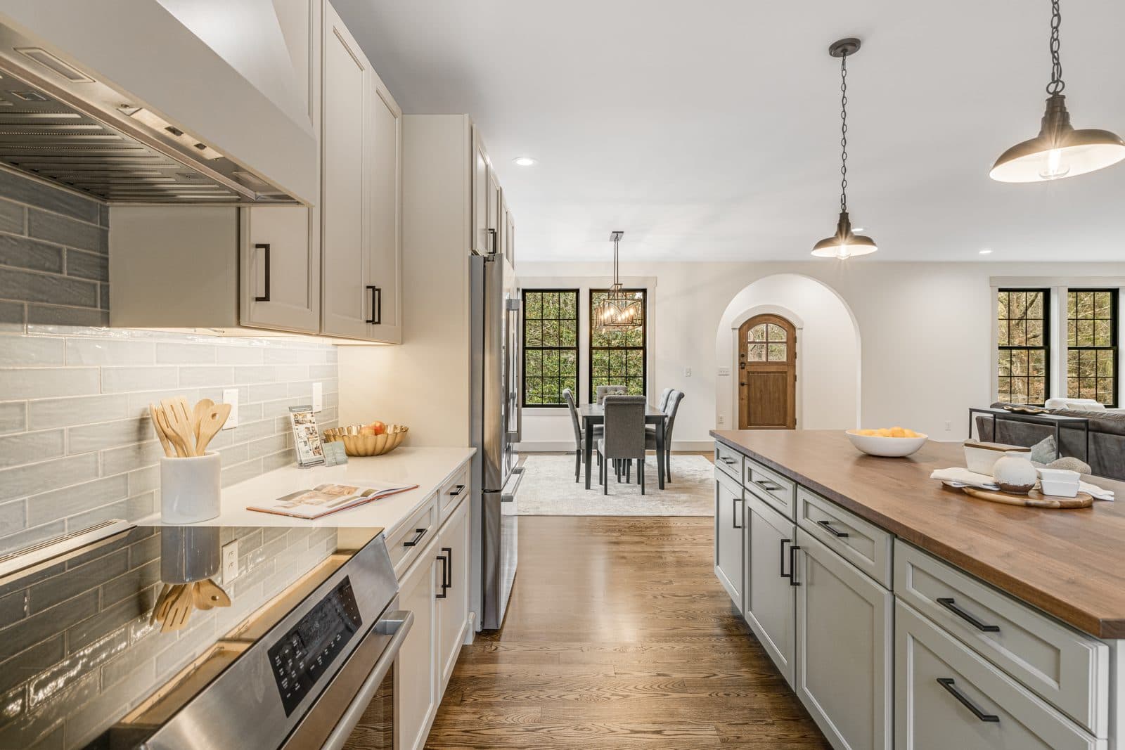 Bright kitchen with a butcher-block island, glass tile backsplash and an arched doorway to the dining room