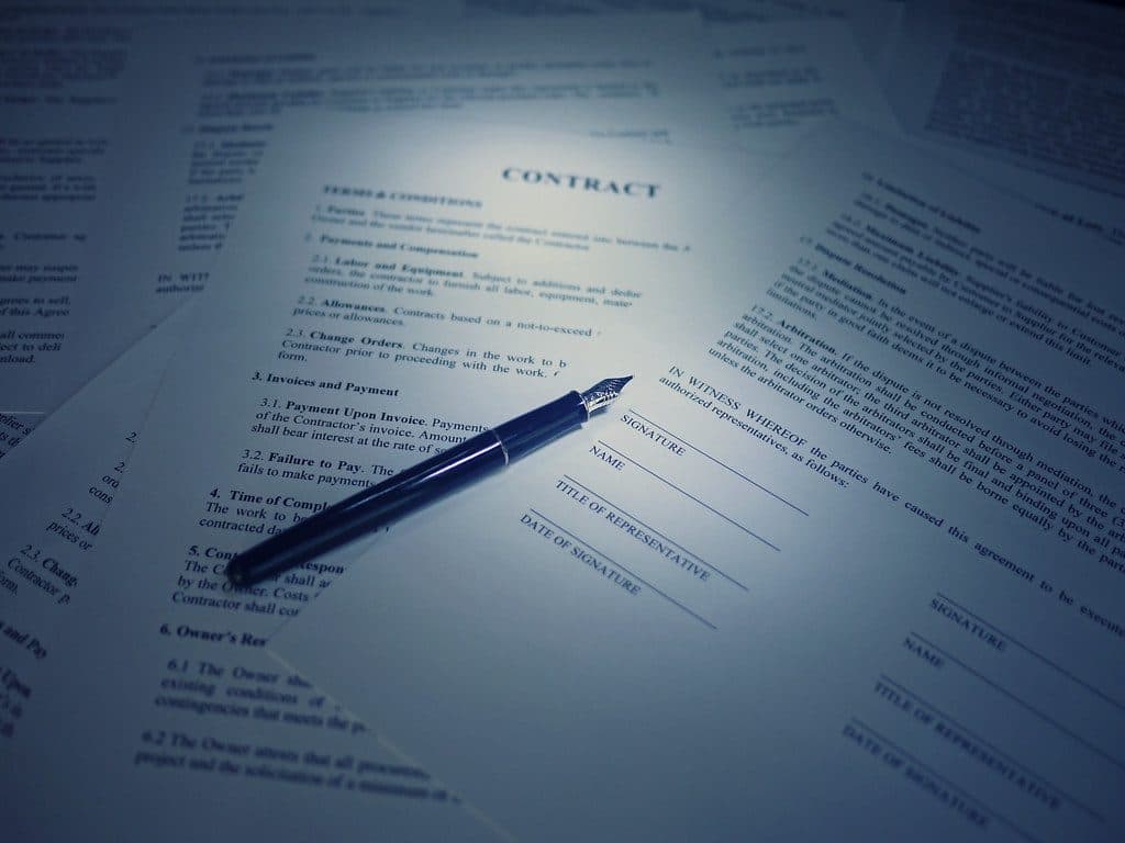 Contract pages spread on a table with a fountain pen resting on a signature line