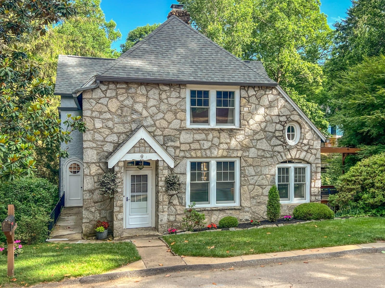 Stone cottage with a steep gabled roof, a small front porch and a few steps up from the walk